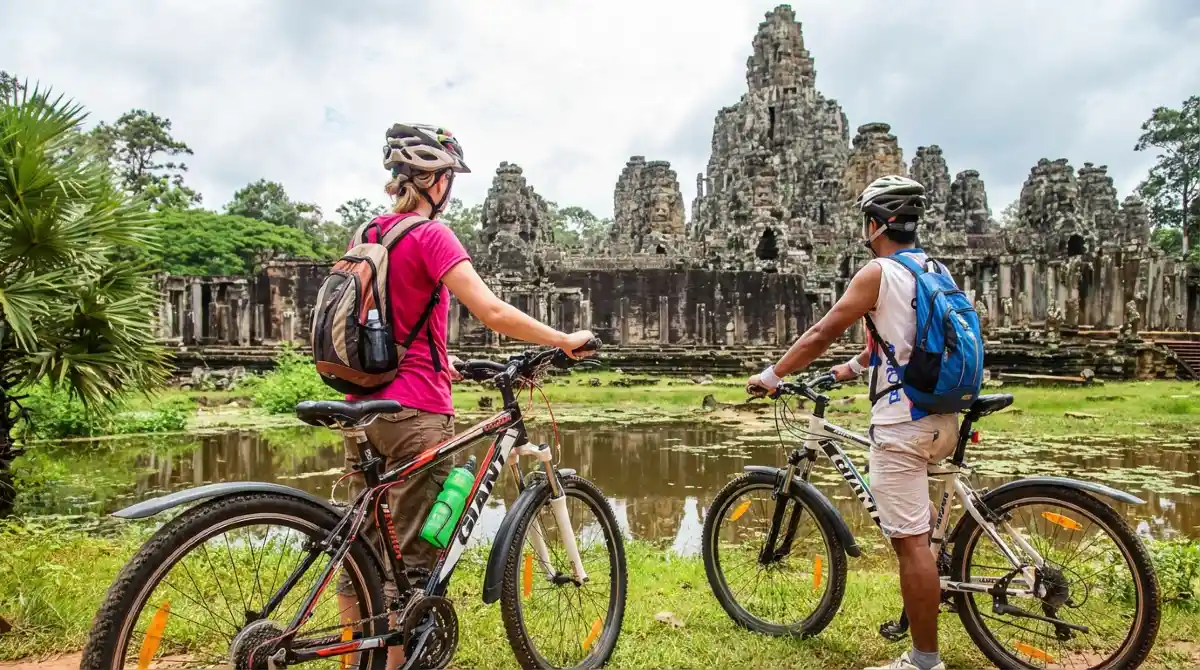Two cyclists with backpacks in front of Bayon Temple